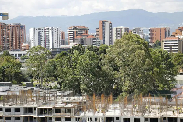 View over El Poblado's brick high-rises with green mountains in the background at golden hour